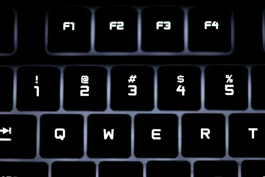 Close de teclado retroiluminado com destaque para as teclas F1 a F4 e as teclas numéricas com símbolos especiais como @, #, $ e %